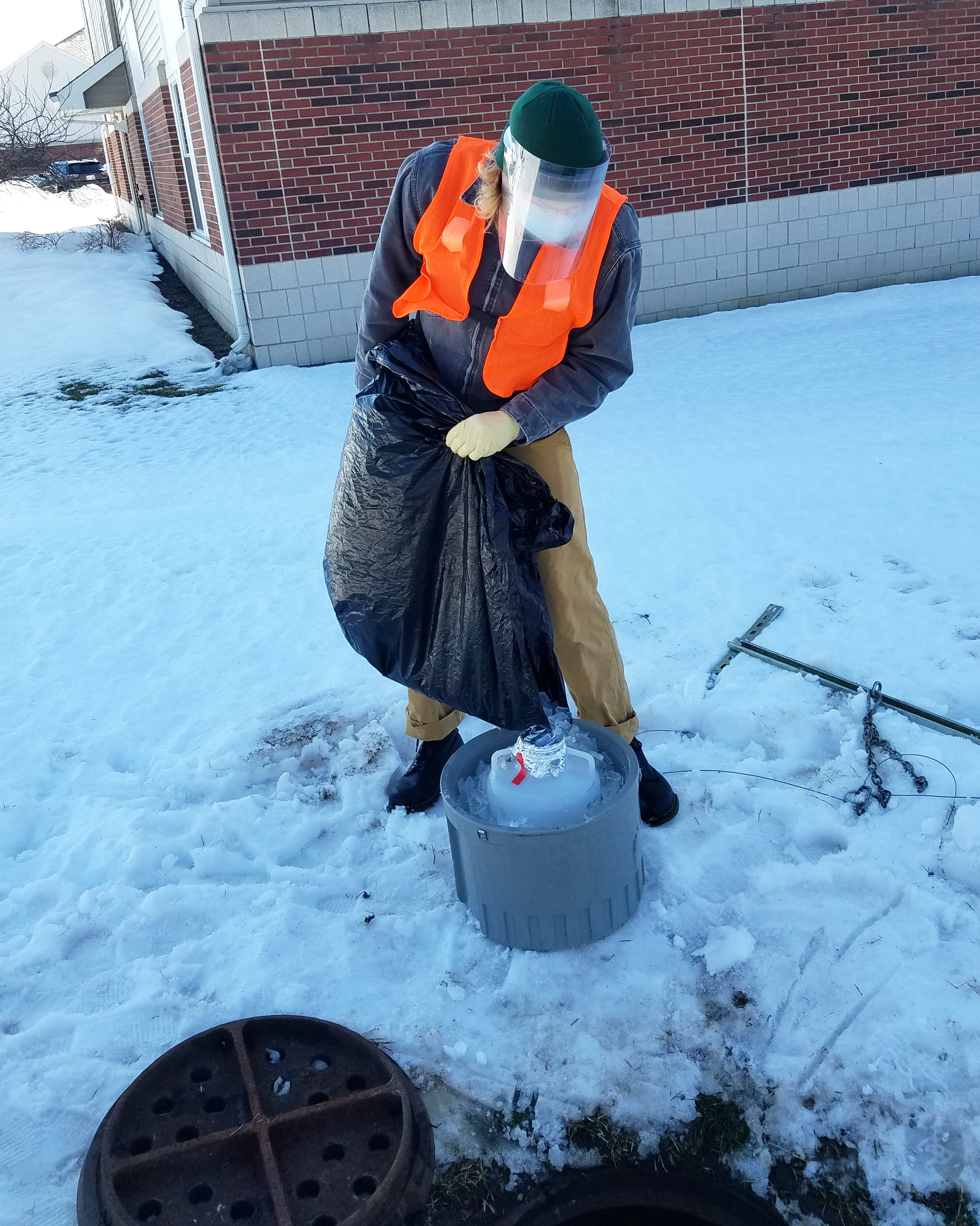 Student packing ice around bottle in snow