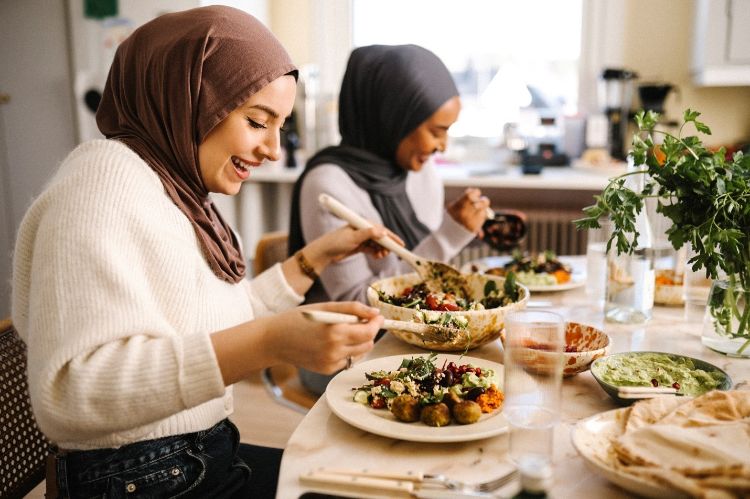 Two people in hijab enjoying a meal.