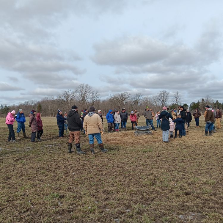 a group of people wearing warm clothing and standing in a brown field