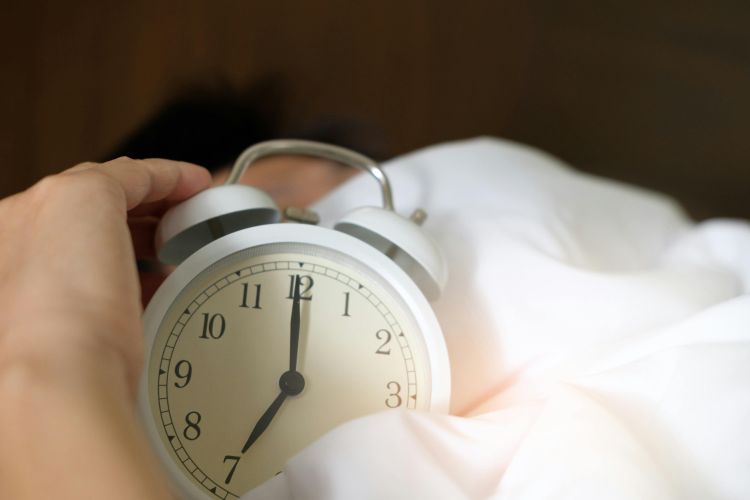 A person touching an alarm clock.