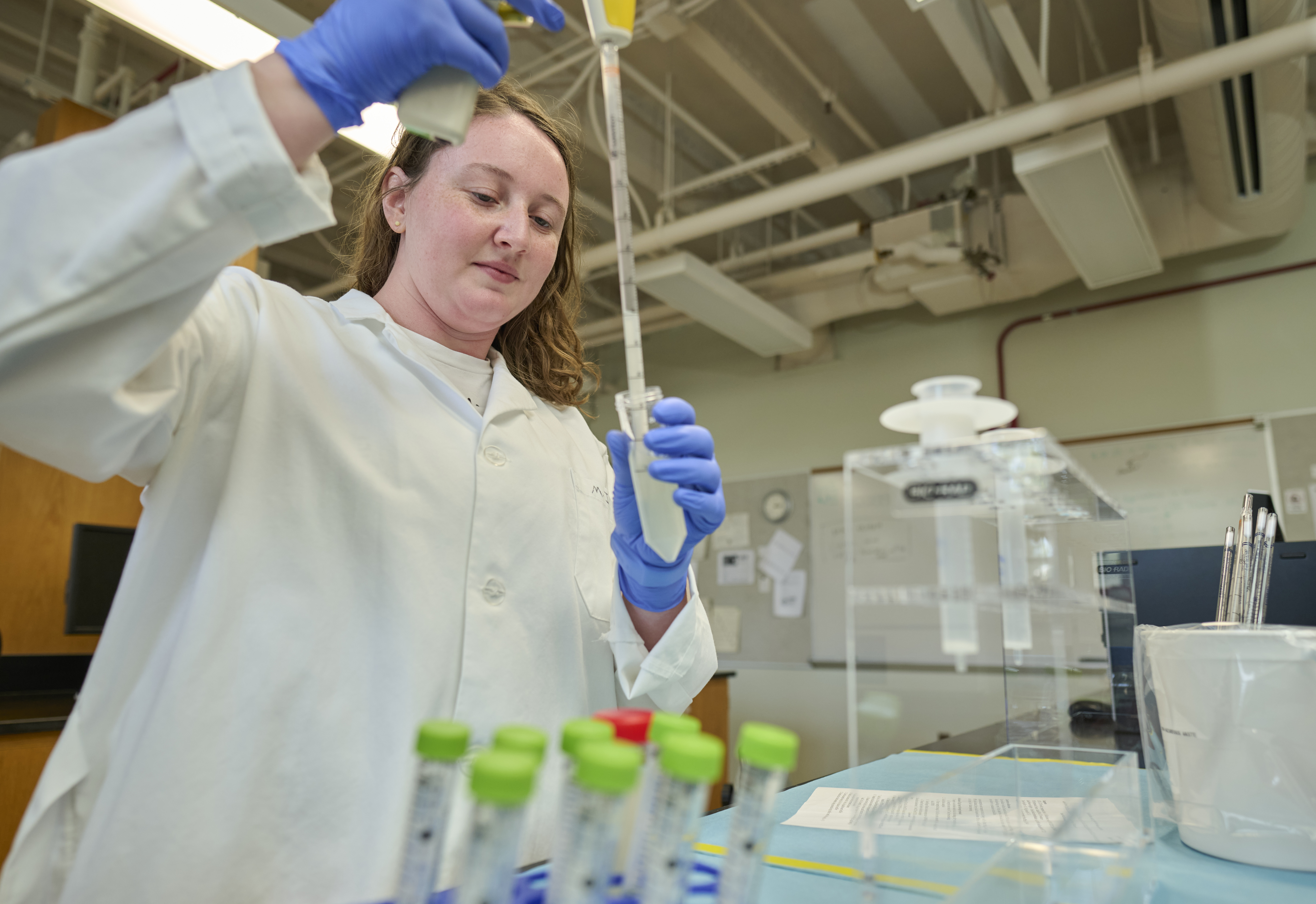 Paiton demonstrates research work in a laboratory setting, wearing a lab coat