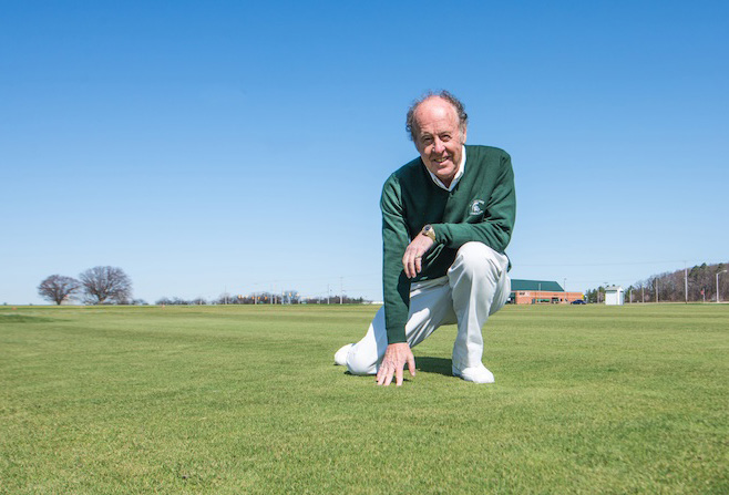 Dr. Joe Vargas kneeling on turfgrass